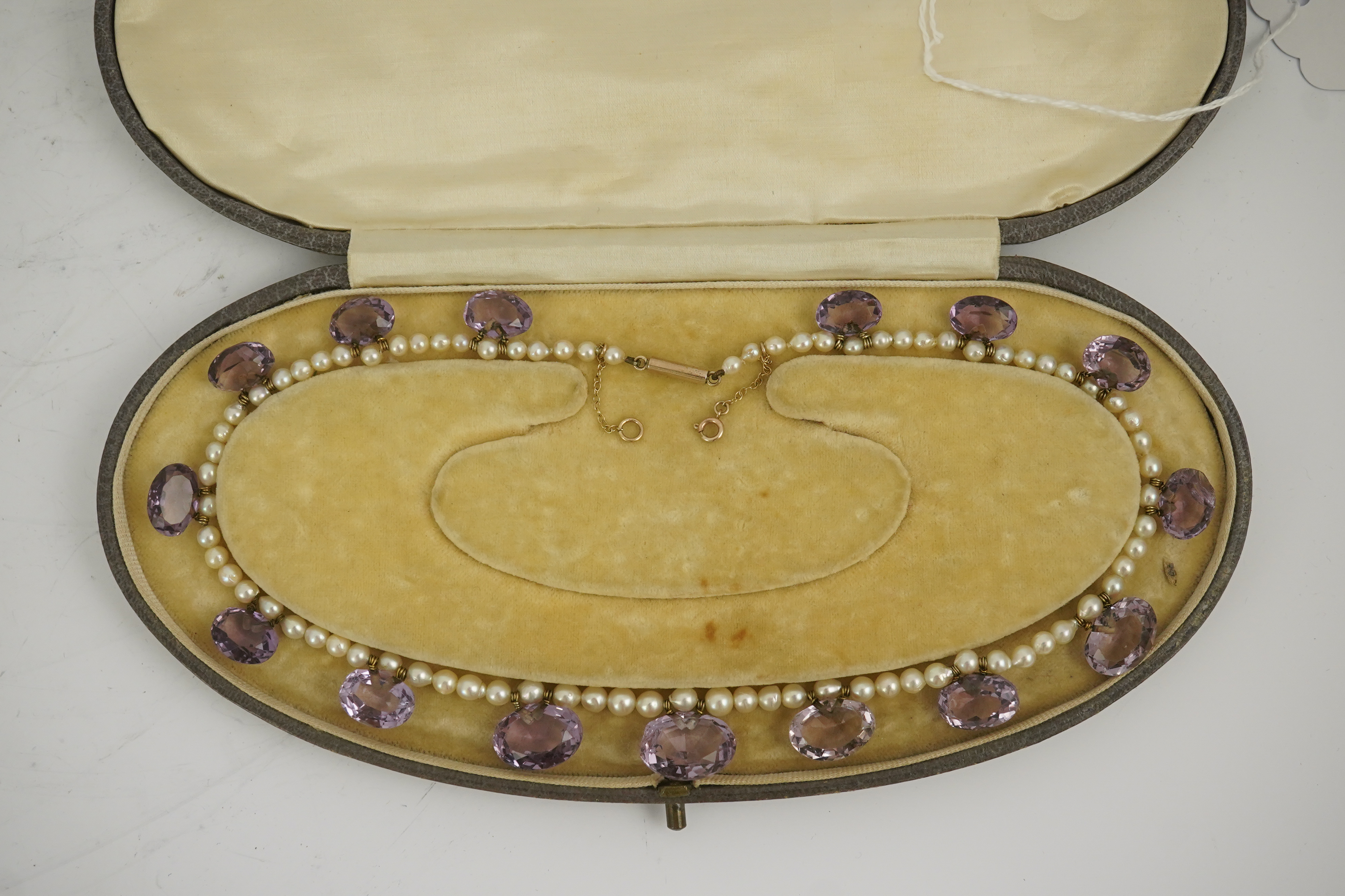 A 19th century pearl and graduated fifteen stone oval cut amethyst set drop necklace, with a gold barrel shaped clasp